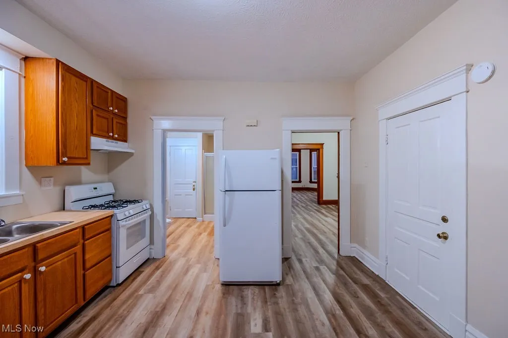 Kitchen with sink, white appliances, and light wood-type flooring