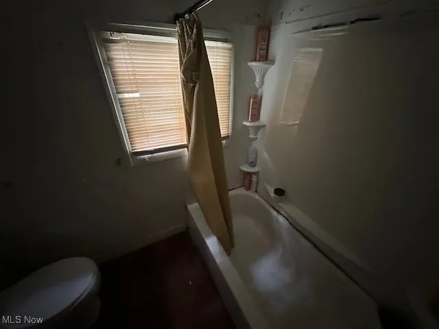 Bathroom featuring shower / bath combination with curtain and toilet