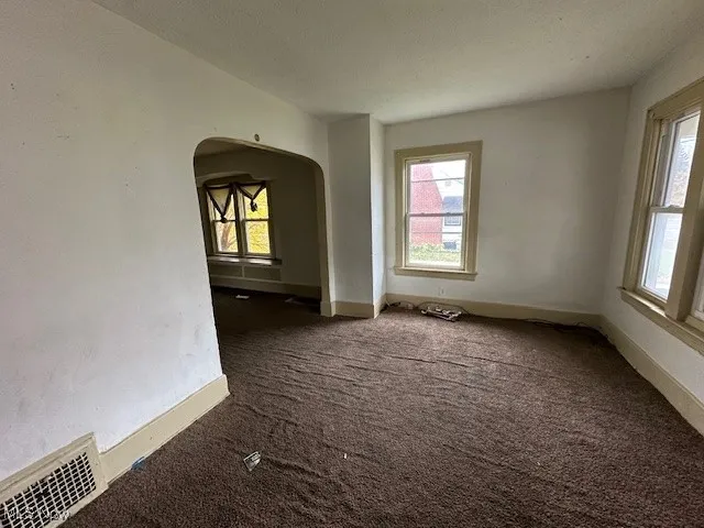 Spare room featuring dark colored carpet and a textured ceiling