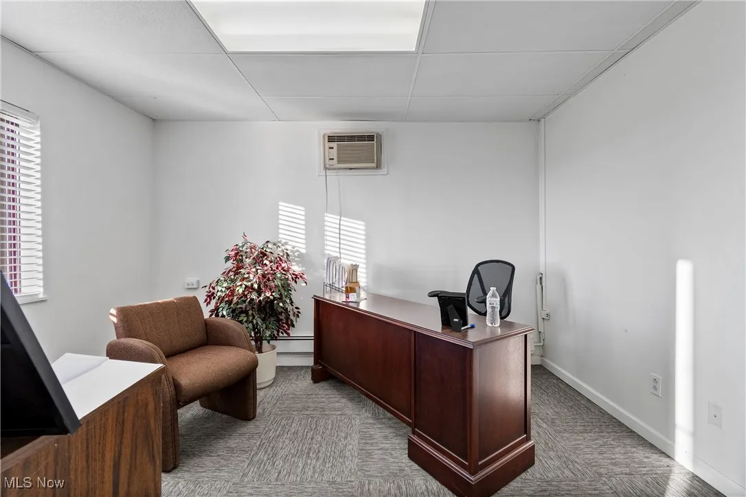 Carpeted home office featuring a drop ceiling and a wall mounted AC