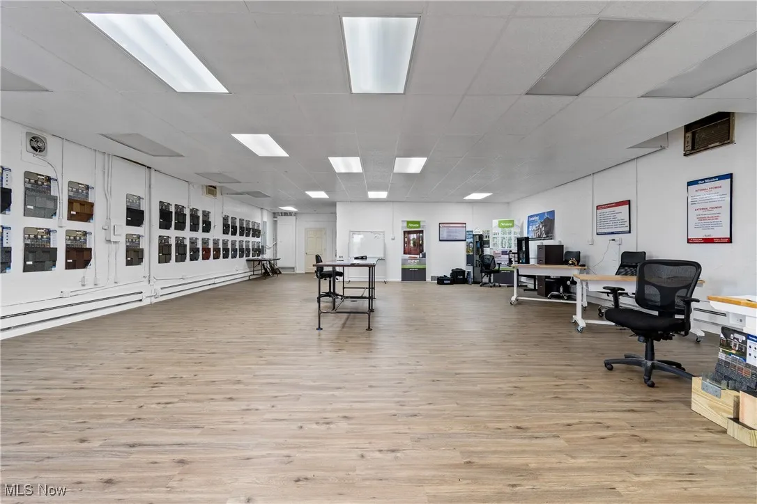 Office with light hardwood / wood-style flooring and a drop ceiling