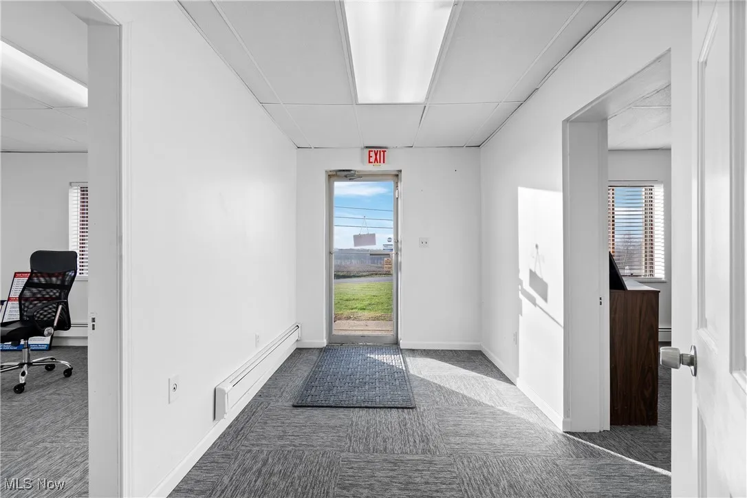 Hall featuring dark colored carpet and a baseboard radiator