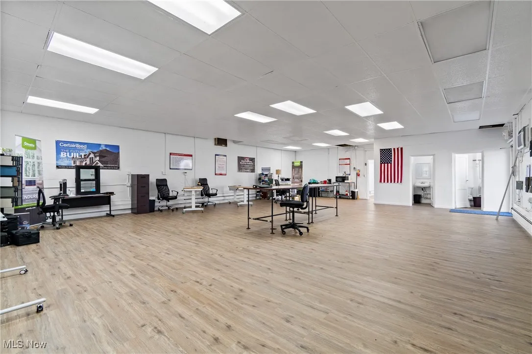 Home office with light wood-type flooring and a paneled ceiling