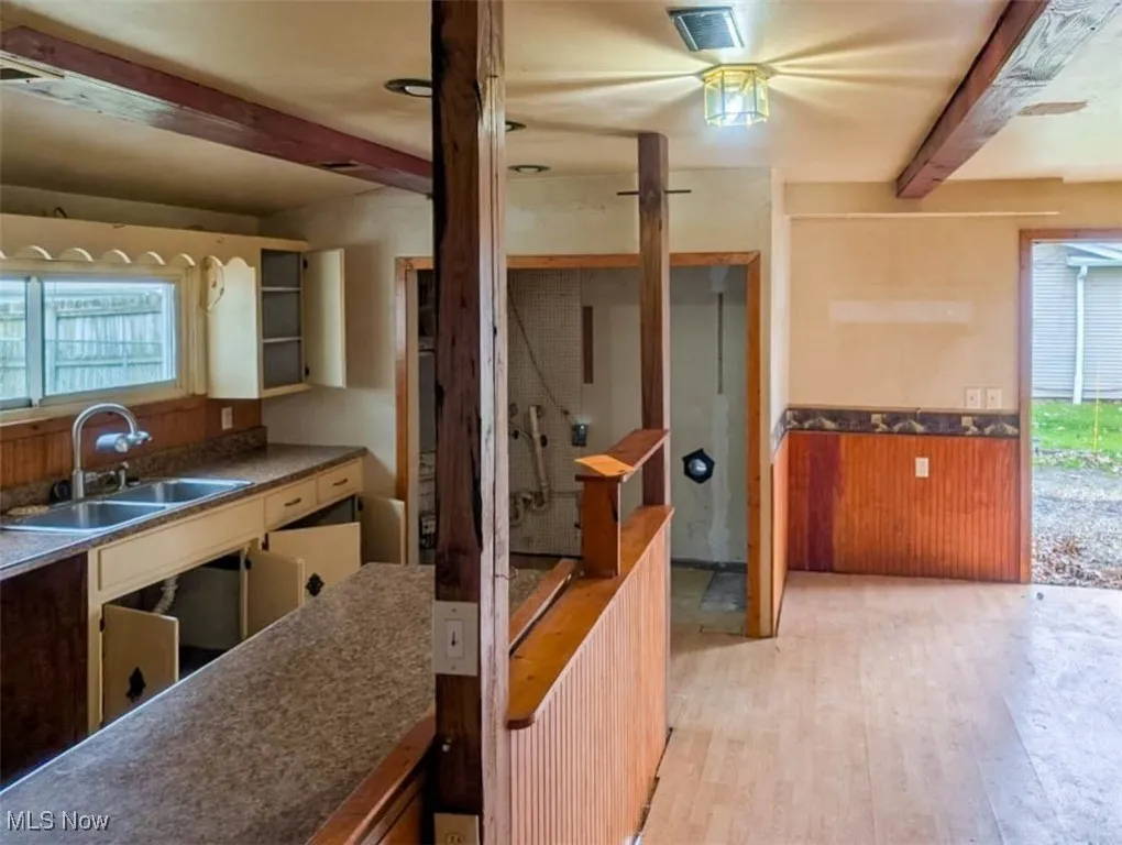 Kitchen featuring sink, beamed ceiling, and light wood-type flooring