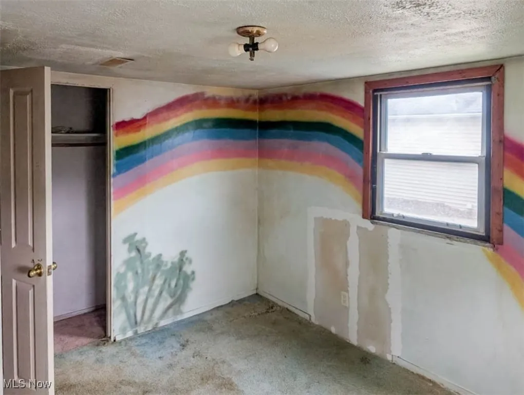 Empty room featuring light colored carpet and a textured ceiling