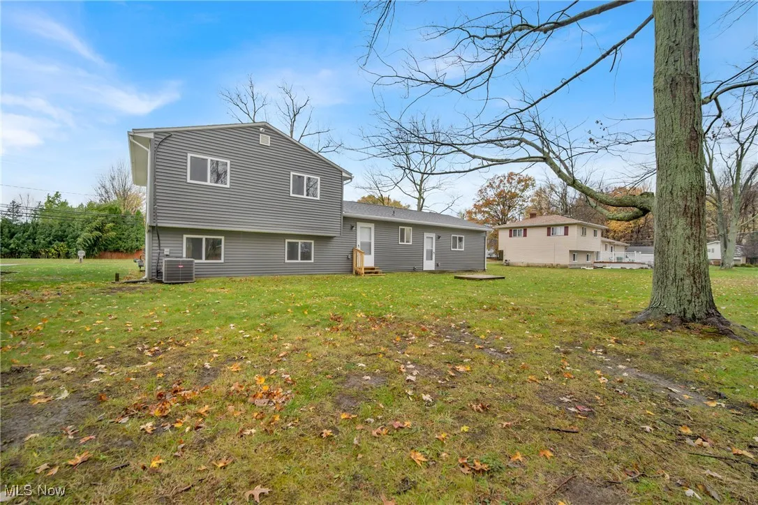 Back of house with a yard and central AC