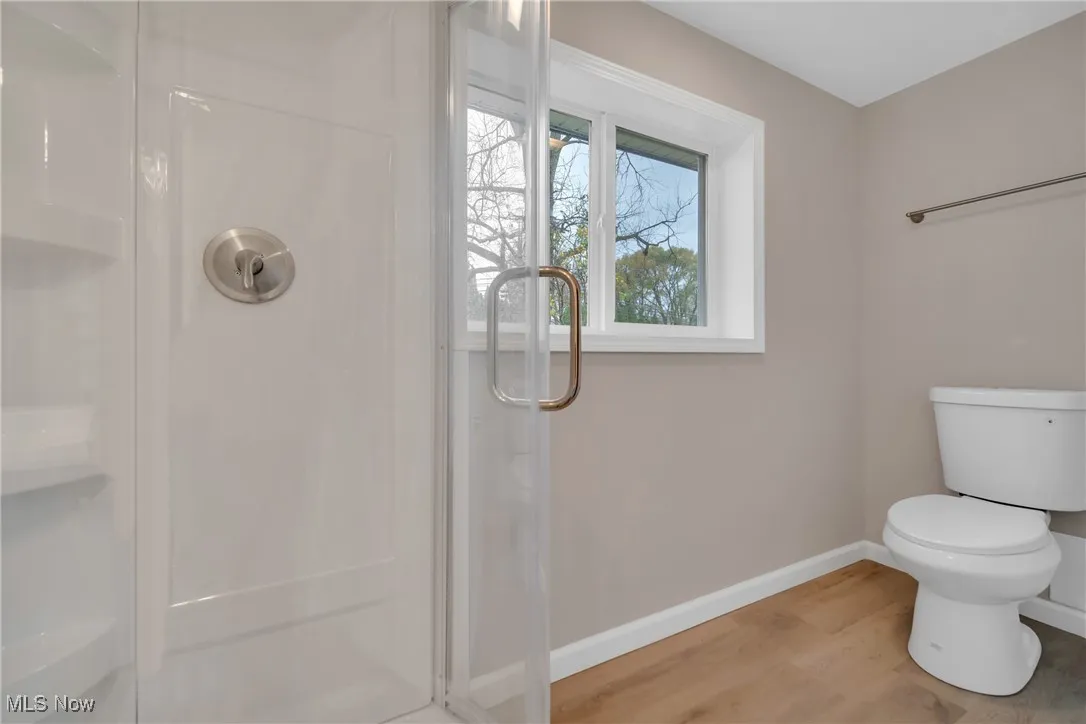 Bathroom featuring toilet, wood-type flooring, and a shower with door