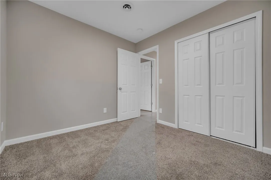 Unfurnished bedroom with light carpet and a closet