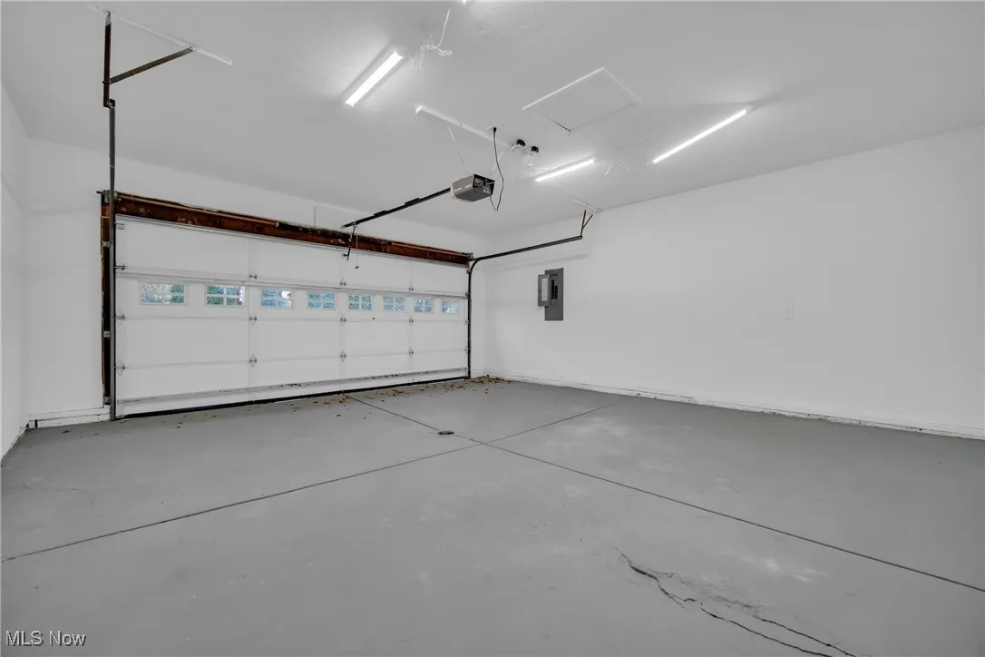 Garage featuring electric panel and a garage door opener