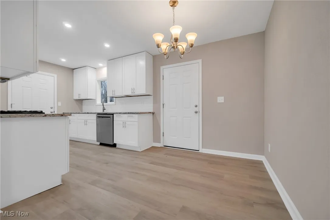 Kitchen featuring decorative light fixtures, light hardwood / wood-style flooring, a notable chandelier, dishwasher, and white cabinetry