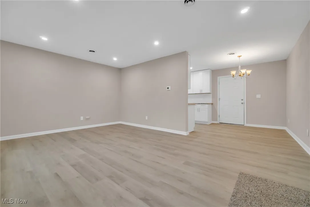Unfurnished living room featuring a notable chandelier and light wood-type flooring