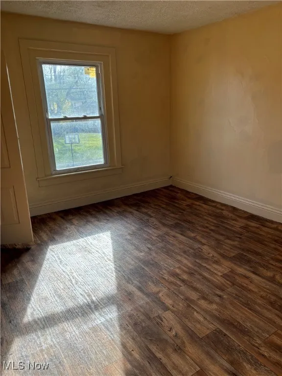 Spare room with dark wood-type flooring and a textured ceiling