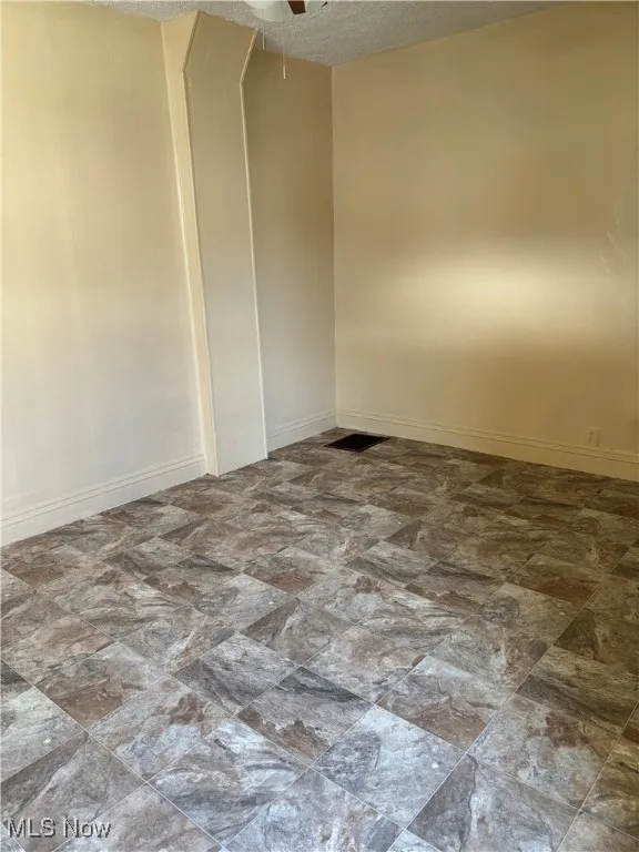Empty room with a textured ceiling and ceiling fan