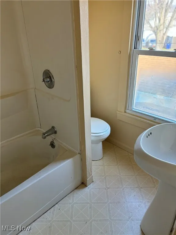 Bathroom with tile patterned floors,  shower combination, and toilet