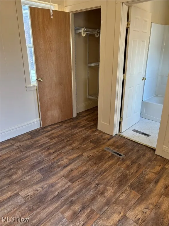 Unfurnished bedroom featuring dark hardwood / wood-style floors and a closet