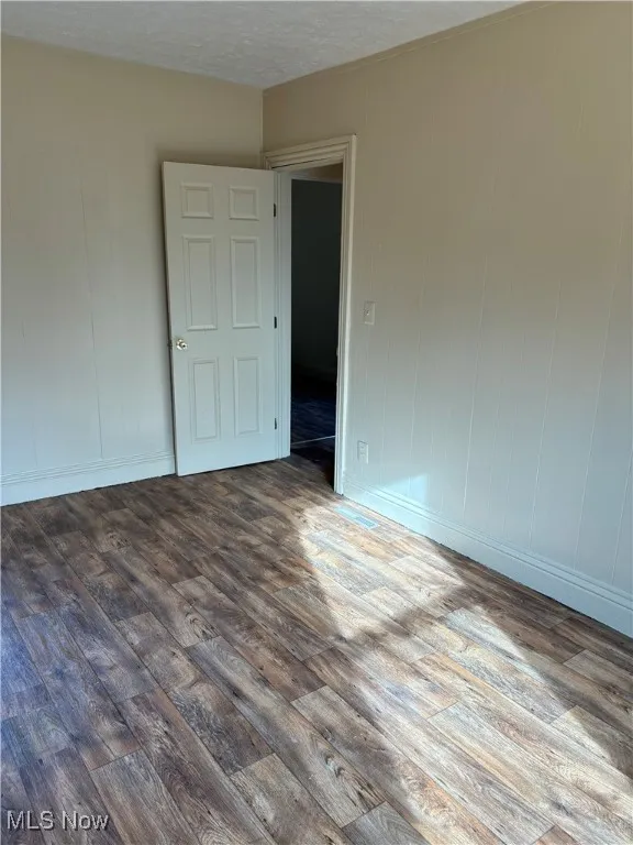 Spare room featuring a textured ceiling and dark hardwood / wood-style floors