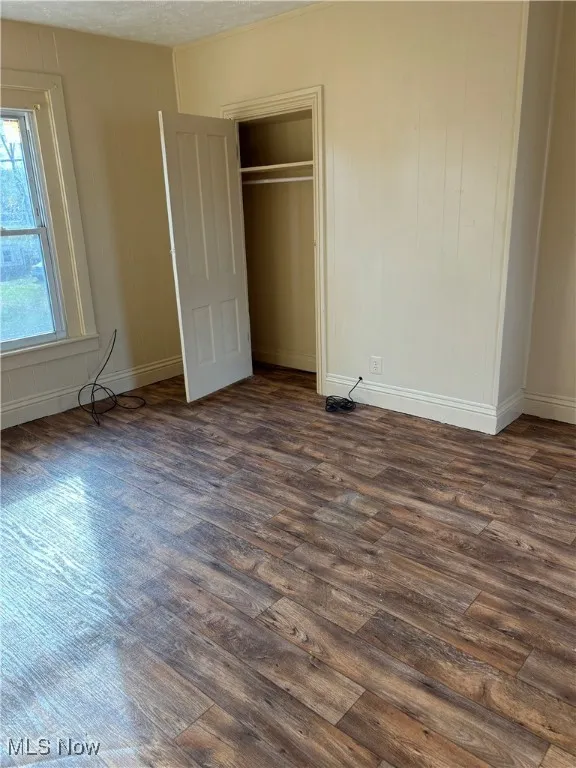 Unfurnished bedroom with a textured ceiling and dark hardwood / wood-style flooring