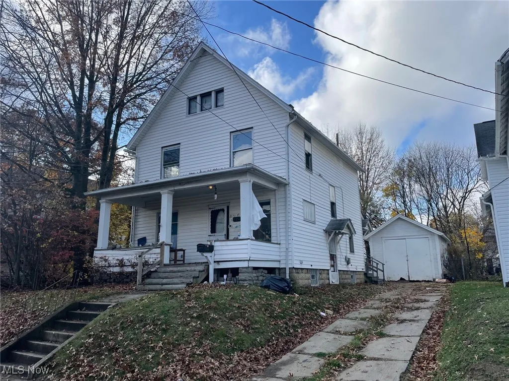 View of front of house with a storage unit and a porch