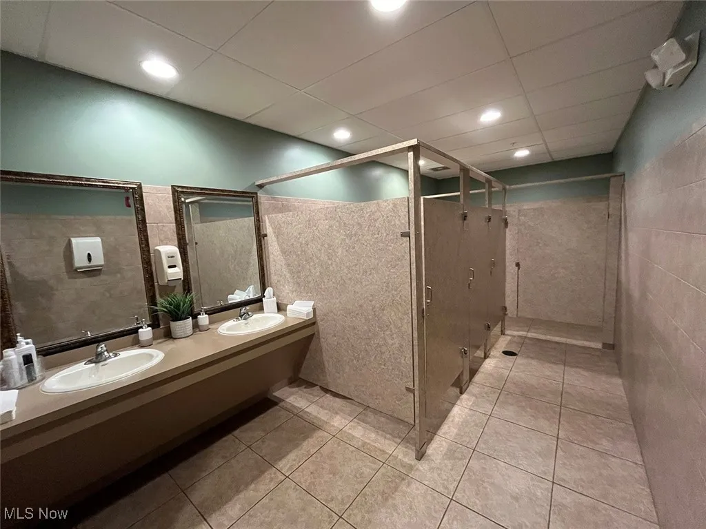Bathroom featuring tile patterned floors, vanity, and tile walls