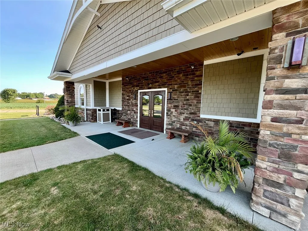 View of exterior entry featuring french doors and a lawn