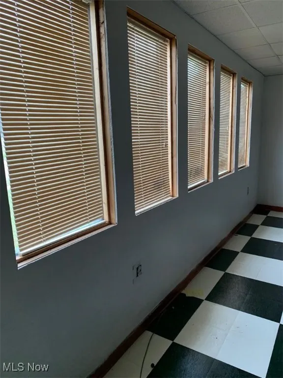 Spare room featuring a wealth of natural light and a drop ceiling