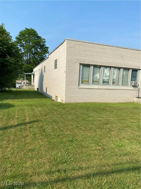 View of property exterior featuring a lawn and cooling unit