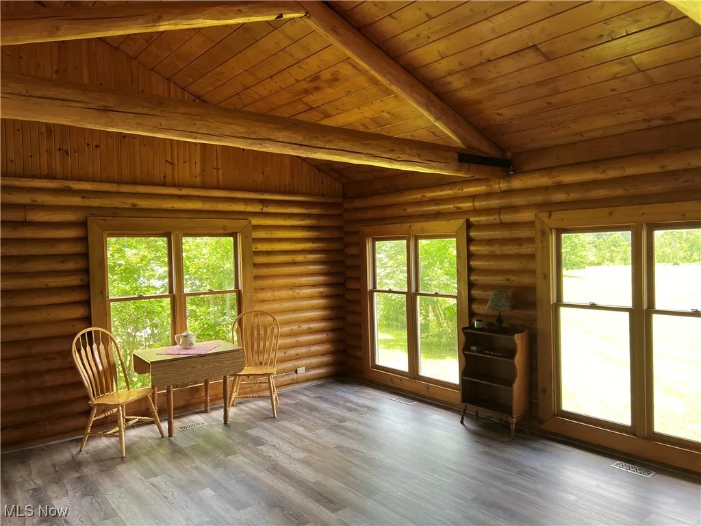 Unfurnished sunroom with vaulted ceiling with beams, a healthy amount of sunlight, and wooden ceiling