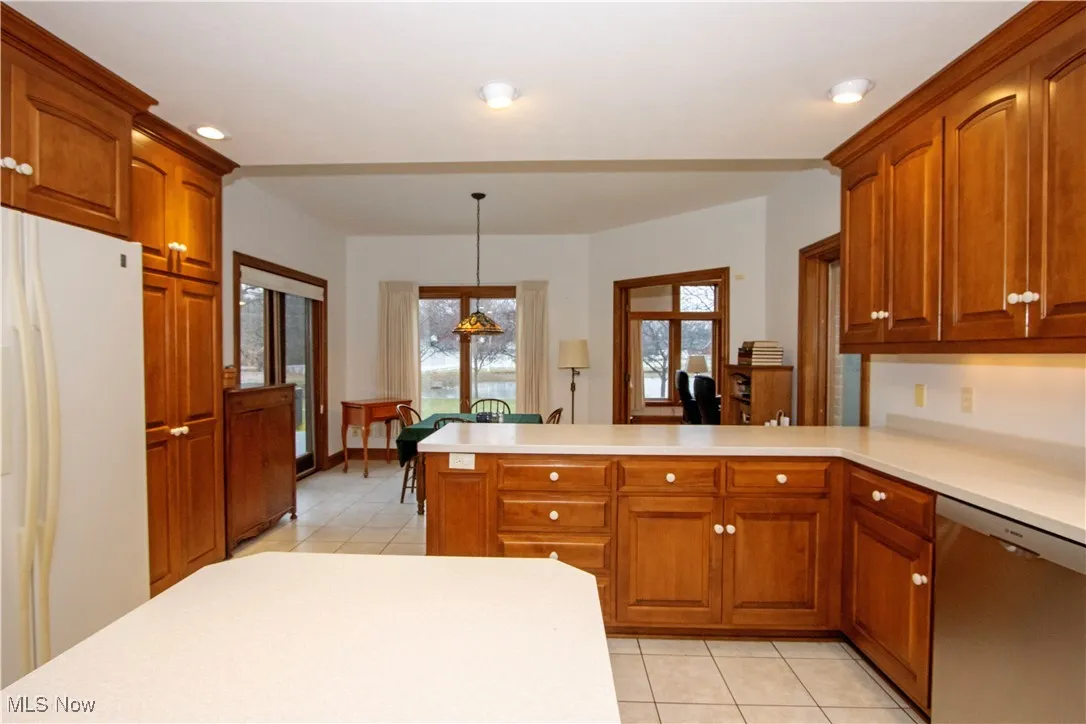 Kitchen with pendant lighting, dishwasher, white refrigerator, kitchen peninsula, and a chandelier