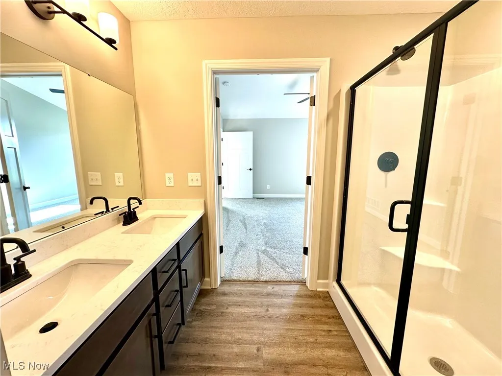 Bathroom featuring hardwood / wood-style floors, vanity, and an enclosed shower