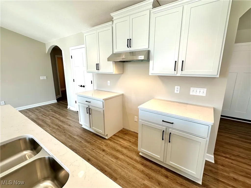Kitchen featuring dark hardwood / wood-style flooring, white cabinetry, and sink