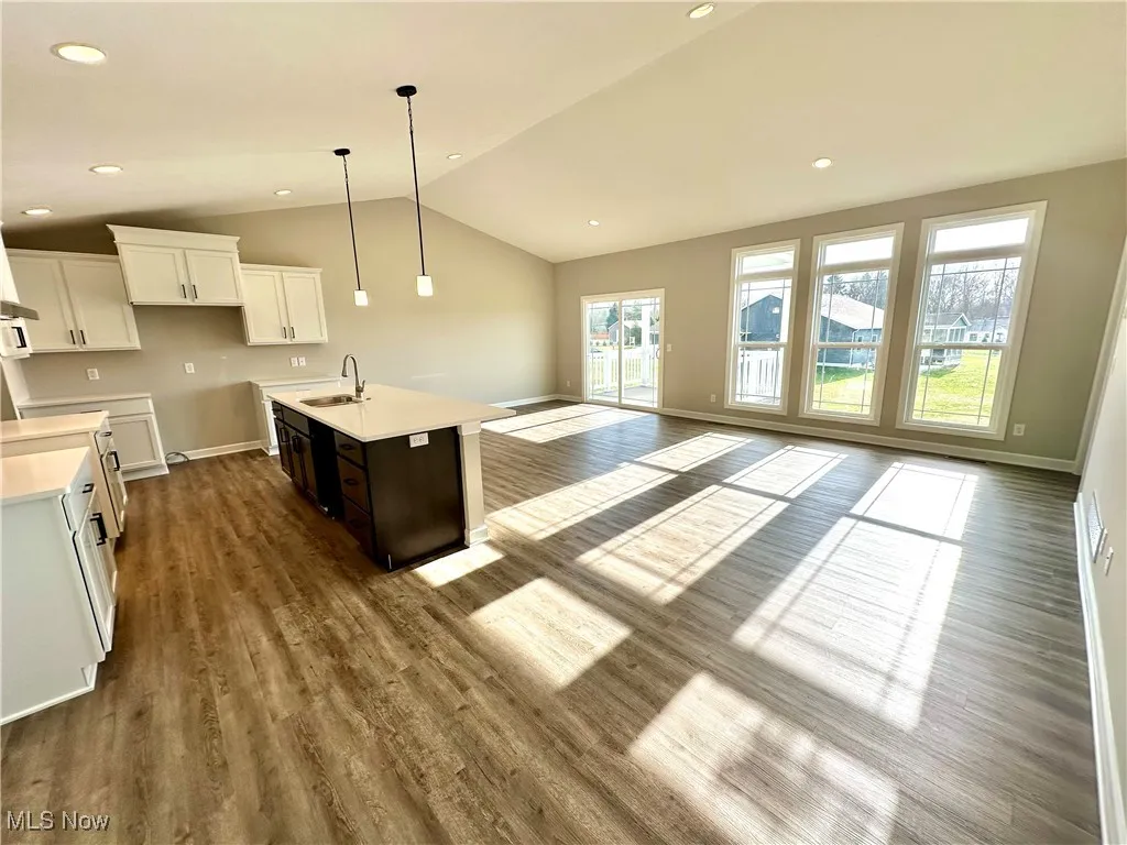 Kitchen featuring lofted ceiling, a kitchen island with sink, sink, dark hardwood / wood-style flooring, and white cabinetry