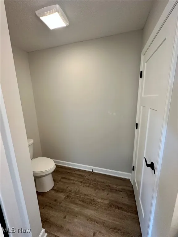 Bathroom featuring hardwood / wood-style floors, toilet, and a textured ceiling