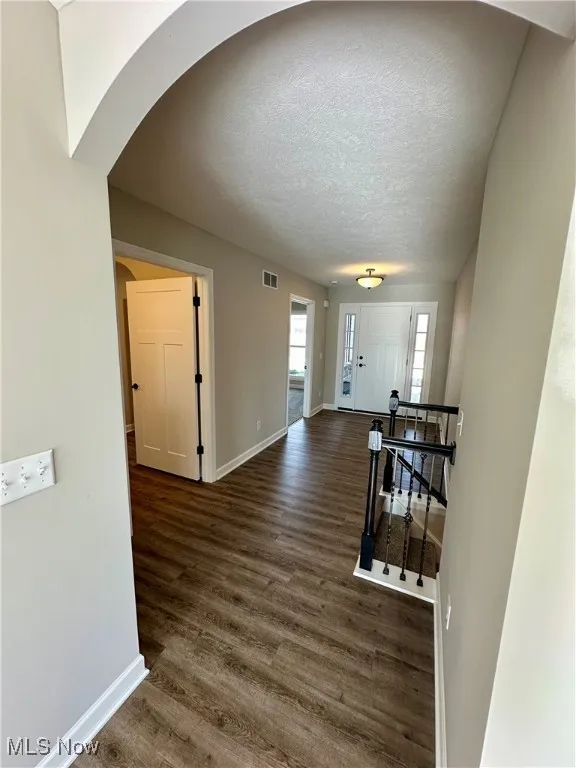 Corridor with dark hardwood / wood-style flooring and a textured ceiling