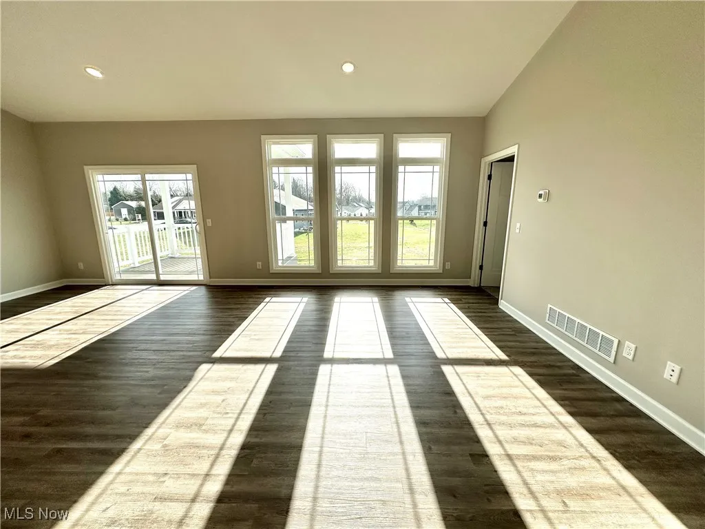 Unfurnished room featuring dark wood-type flooring and lofted ceiling