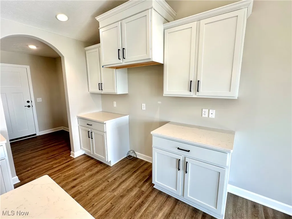 Kitchen featuring white cabinetry, dark wood-type flooring, and light stone counters
