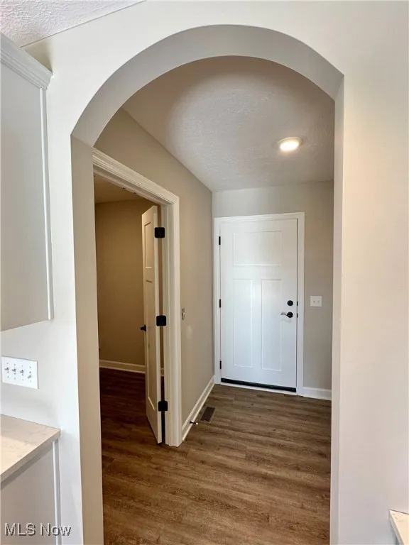 Corridor featuring a textured ceiling and dark hardwood / wood-style floors