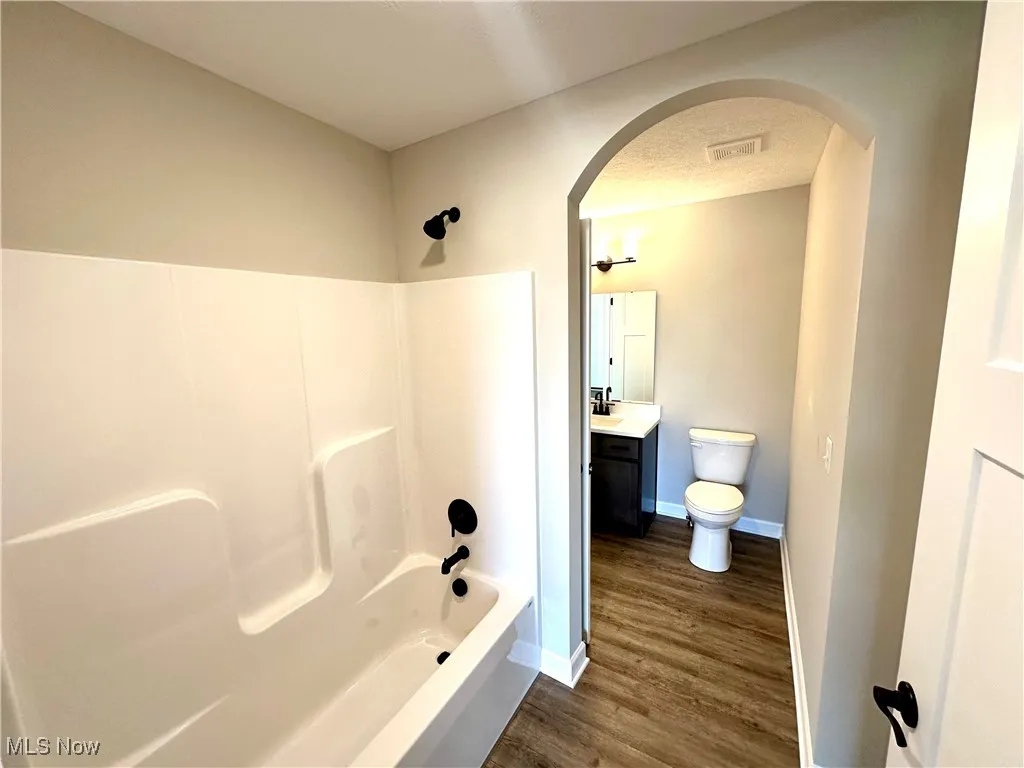 Full bathroom featuring hardwood / wood-style floors, a textured ceiling, toilet, vanity, and shower / bathtub combination