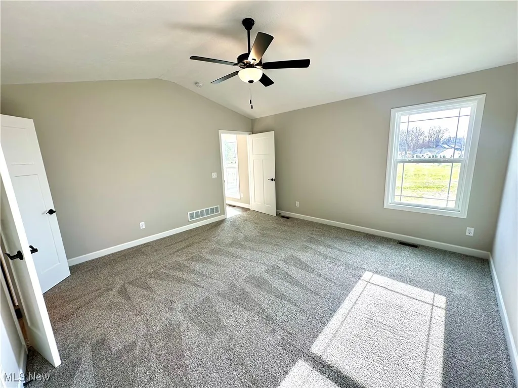 Unfurnished bedroom featuring carpet, ceiling fan, and lofted ceiling