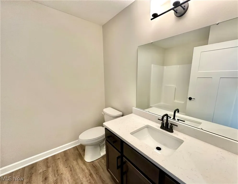 Bathroom featuring hardwood / wood-style flooring, vanity, toilet, and a shower