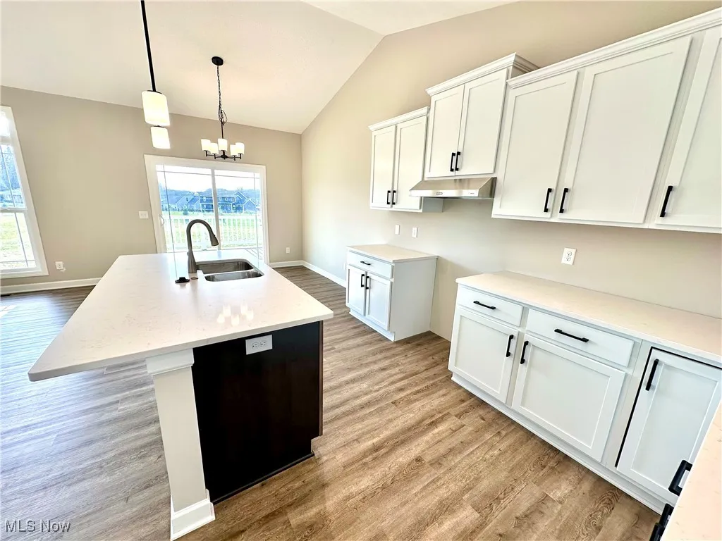 Kitchen with white cabinets, a center island with sink, plenty of natural light, and sink
