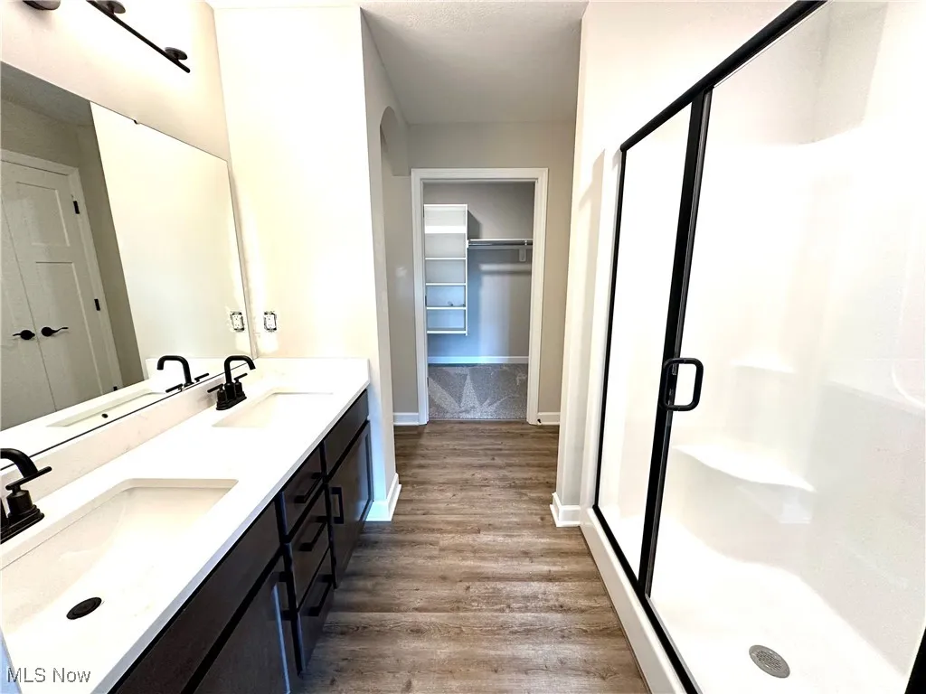 Bathroom featuring vanity, hardwood / wood-style flooring, and a shower with door