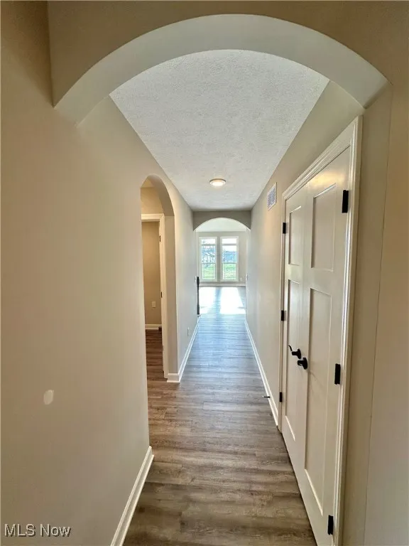 Hallway with a textured ceiling and hardwood / wood-style flooring