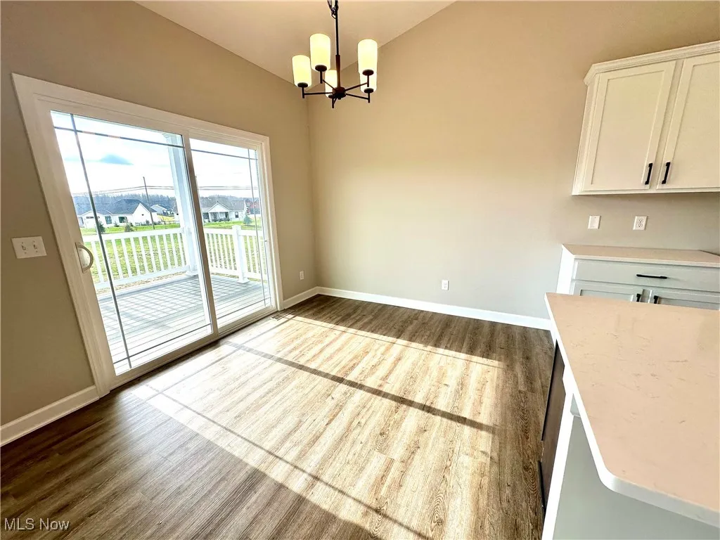 Unfurnished dining area with vaulted ceiling, dark hardwood / wood-style flooring, and an inviting chandelier