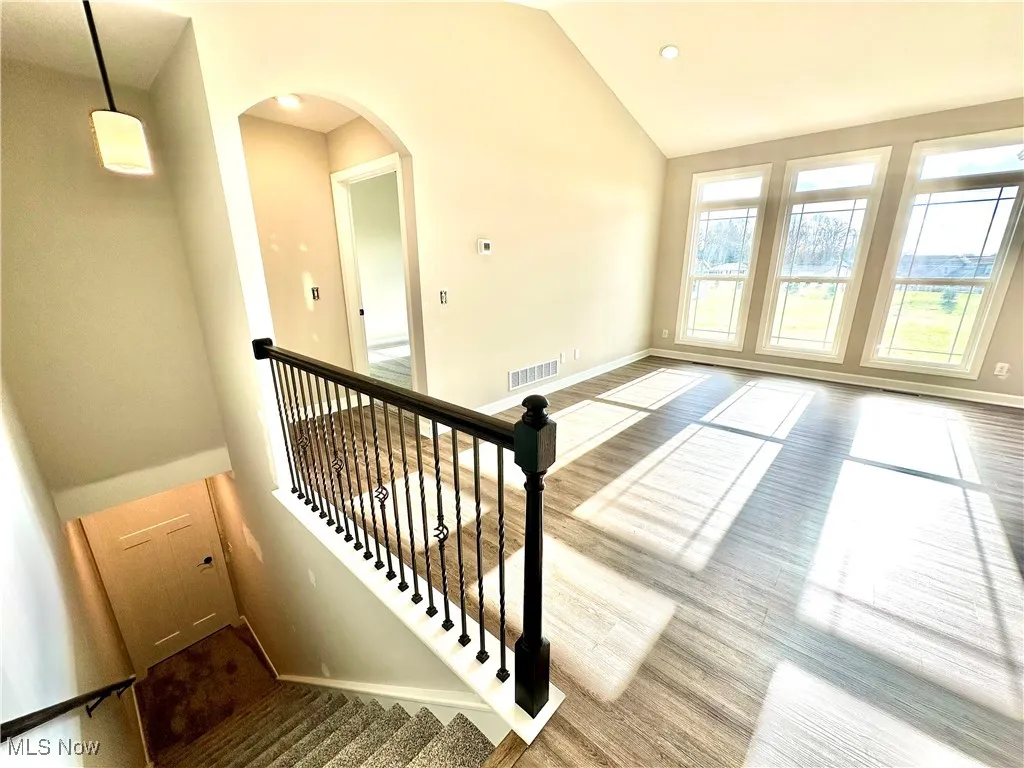 Staircase with hardwood / wood-style floors and high vaulted ceiling