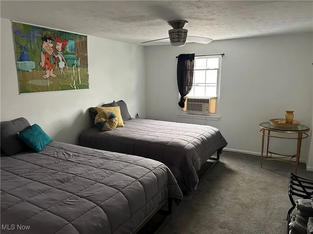Bedroom featuring a textured ceiling, carpet floors, ceiling fan, and cooling unit