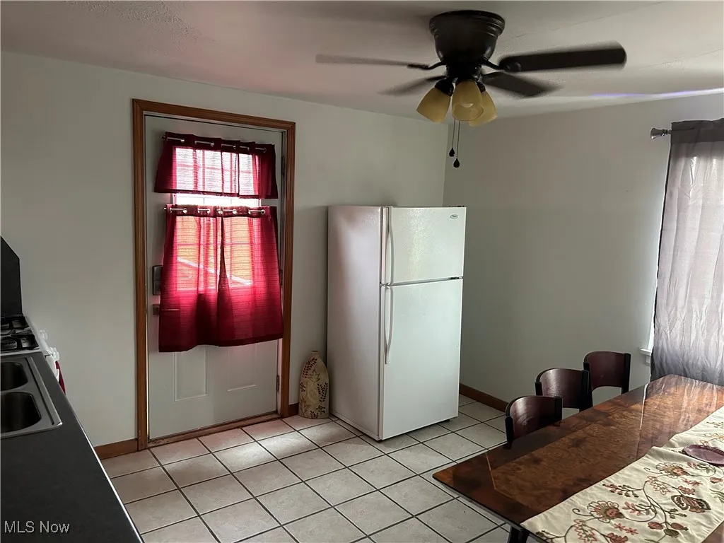 Kitchen with ceiling fan, sink, light tile patterned floors, and white refrigerator