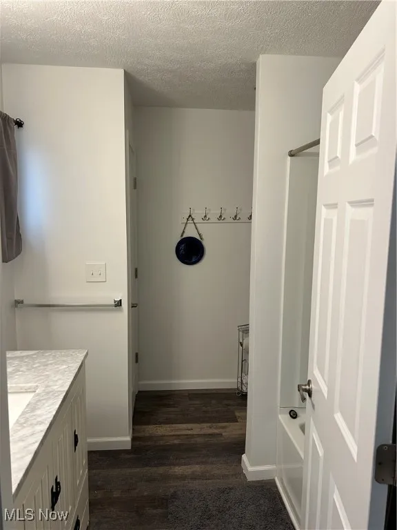 Bathroom with hardwood / wood-style floors, vanity, and a textured ceiling