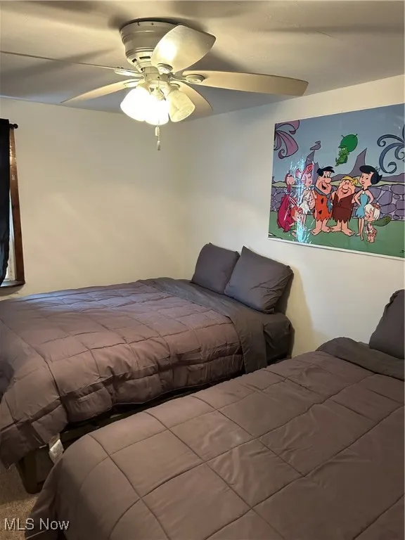 Carpeted bedroom featuring ceiling fan