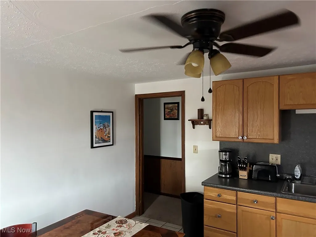 Kitchen featuring ceiling fan, sink, light tile patterned floors, and a textured ceiling