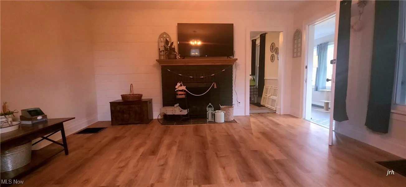 Living area featuring wood finished floors, a brick fireplace, and baseboards